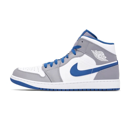 Lateral profile view of the Jordan 1 Mid True Blue sneaker featuring a white leather upper, cement grey overlays and ankle collar, dark blue Swoosh and laces, and a white midsole with a blue rubber outsole.