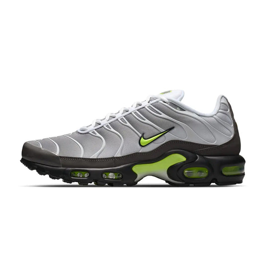Lateral profile view of the Nike Air Max Plus Neon sneaker featuring a gradient grey mesh upper, white wavy TPU overlays, mini neon volt Swoosh, black midsole, volt midfoot shank, and visible volt Tuned Air units.