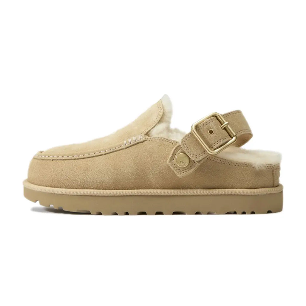 Lateral side view of the UGG Goldenstar Evelina Clog in Sand Castle featuring a beige suede upper, plush cream shearling lining, an adjustable heel strap with a metallic buckle, and a matching beige platform sole.
